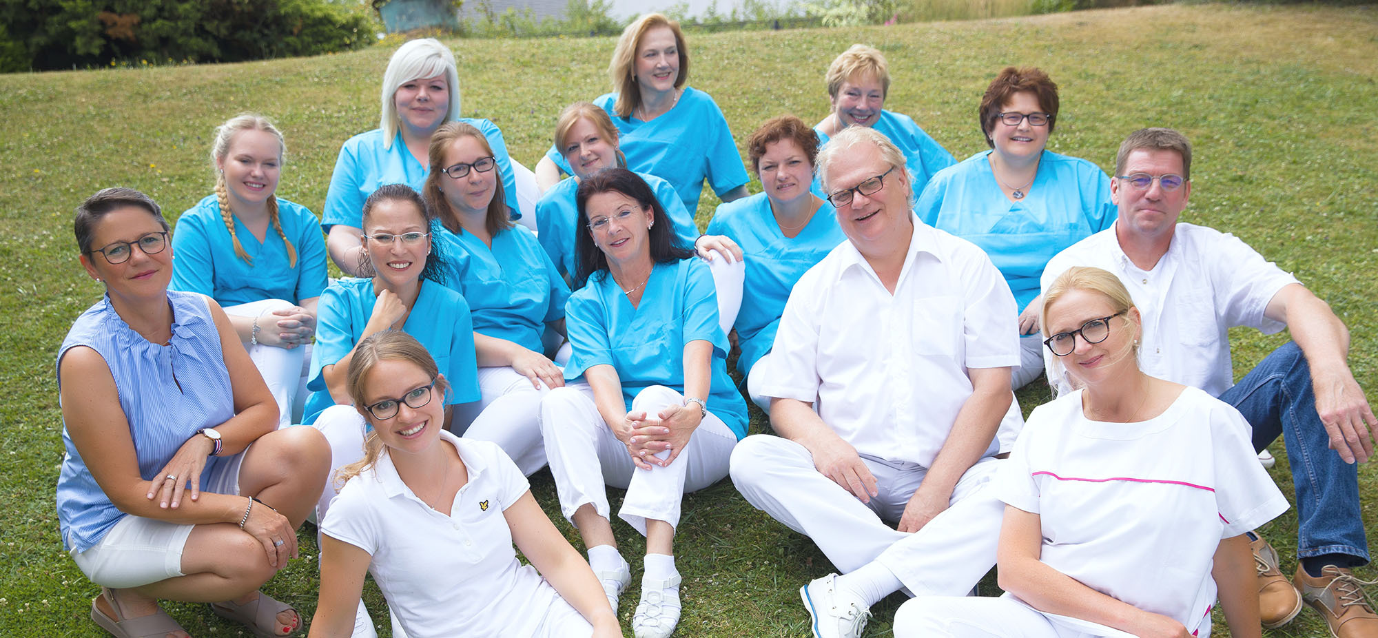 Das Team der Zahnarztpraxis Thiele & Menk in Weilburg: Gruppe von Zahnärzten und Mitarbeiterinnen im blauen und weißen Praxisoutfit, die auf der Wiese posieren, repräsentiert die moderne und persönliche Zahnmedizin der Praxis.