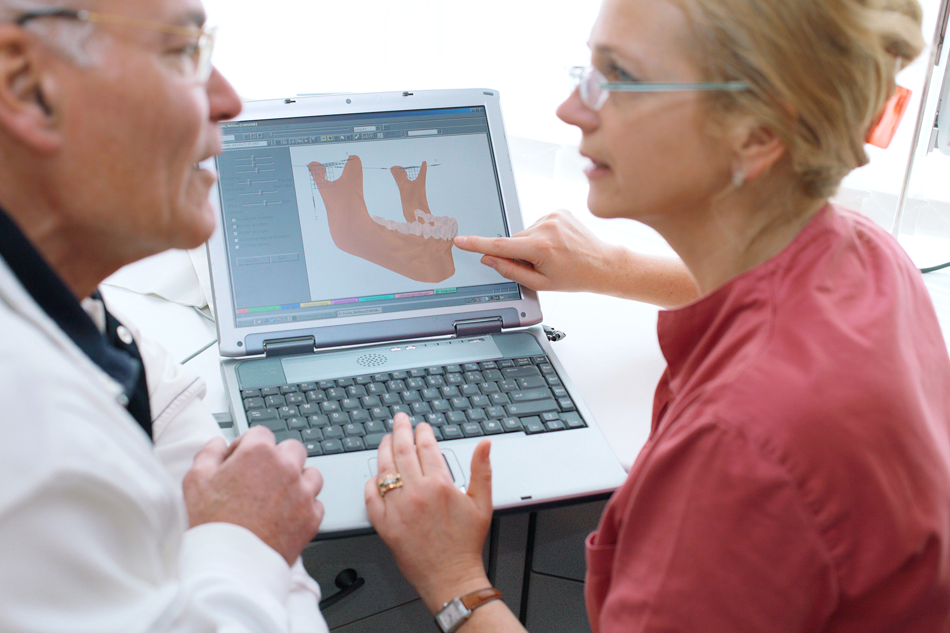 Zahnarztpraxis Thiele & Menk: Patientin und Zahnarzt betrachten 3D-Dentalmodell auf Laptop zur verständlichen Aufklärung über zahnmedizinische Behandlungen.