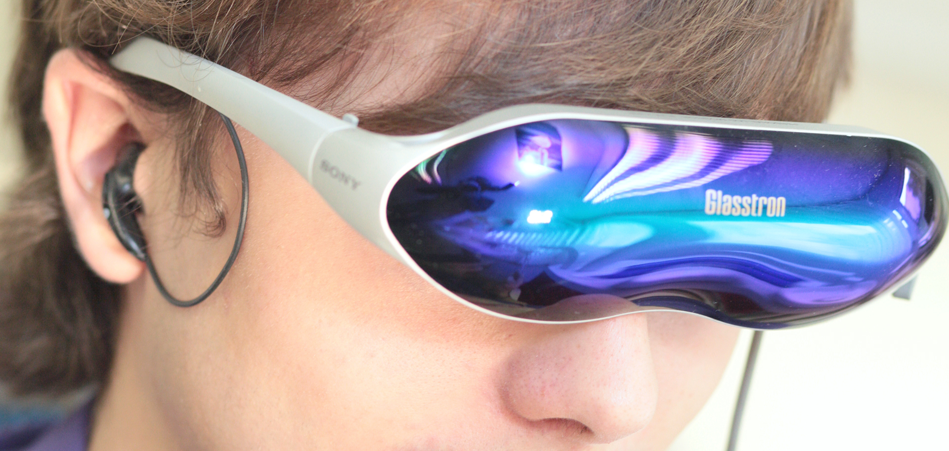Eine Person trägt eine Sony-Glasstron-Datenbrille mit brillantem Display sowie ein Bluetooth-Headset – ein Beispiel für moderne Technologie, wie sie in Zahnarztpraxen wie „Die Zahnarztpraxis Thiele & Menk“ in Weilburg zum Einsatz kommt.
