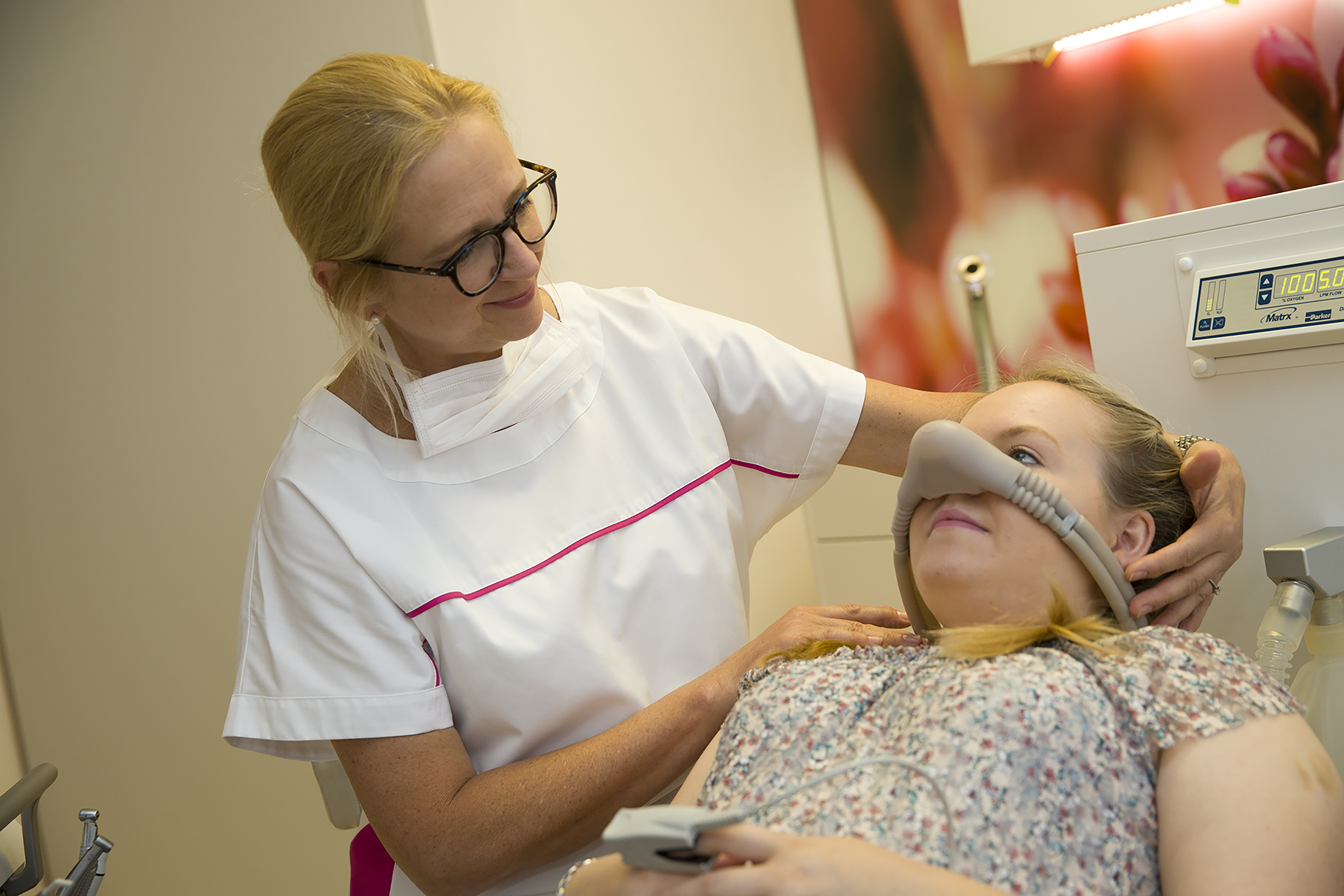 In der Zahnarztpraxis Thiele & Menk in Weilburg assistiert eine Zahnärztin einer Patientin mit einer Lachgasmaske während einer zahnmedizinischen Behandlung, die moderne Zahnmedizin und persönliche Betreuung kombiniert.