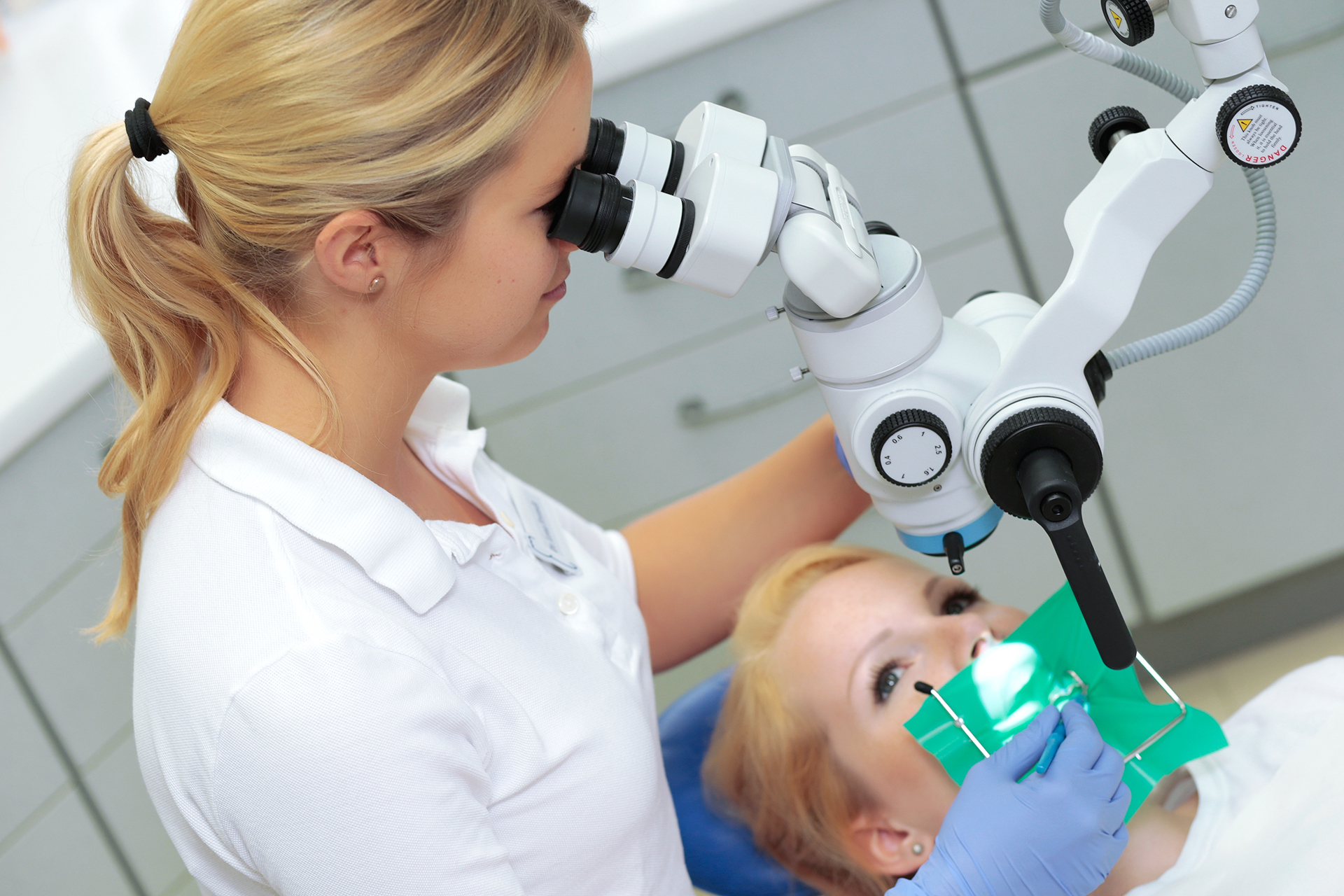 Zahnärztin in der Zahnarztpraxis Thiele & Menk in Weilburg nutzt ein Mikroskop für eine präzise zahnmedizinische Behandlung bei einer Patientin.